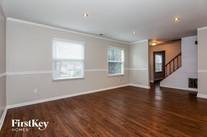 Charlotte house for rent - a living room with wood floors and white walls and a staircase