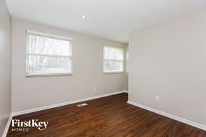 Charlotte house for rent - a bedroom with white walls and wood flooring and two windows