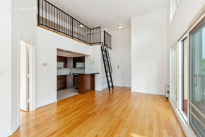 Brooklyn apartment for rent - A wooden floor in a white room with a black railing.