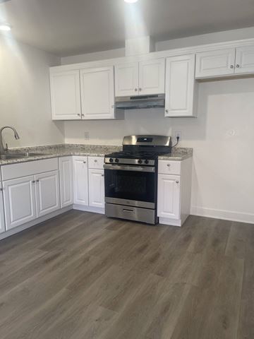 Northridge apartment for rent - a kitchen with white cabinets and stainless steel appliances and a wooden floor