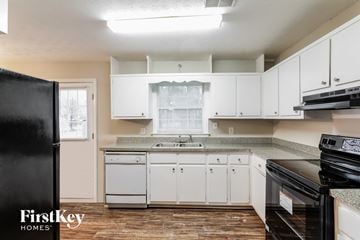 Snellville house for rent - a kitchen with white cabinets and a black stove and refrigerator