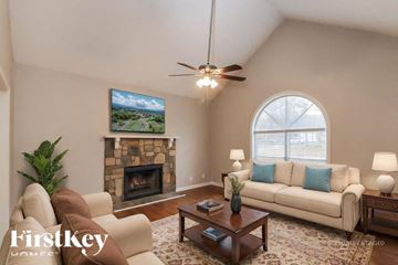 Dacula house for rent - A living room with a stone fireplace and a painting of a landscape above it.