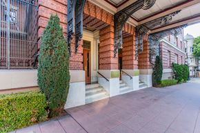 San Francisco apartment for rent - A red brick building with a black iron gate and a green tree.