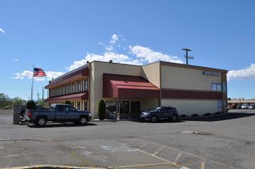 Yakima apartment for rent - A building with a flag on top and cars parked in front.
