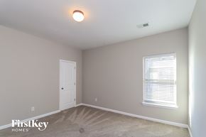 Cumming house for rent - a bedroom with a white door and a window and a carpeted floor