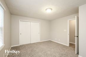 Fishers house for rent - a bedroom with white walls and carpet and a door to a closet