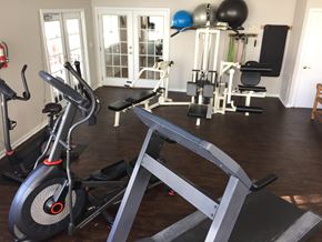 St. Petersburg apartment for rent - A home gym with a variety of equipment including a stationary bike, a leg press machine, and a bench press.