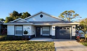 St. Petersburg house for rent - a white house with a driveway and a black garage door