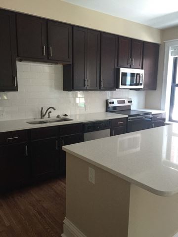 St. Louis apartment for rent - A kitchen with dark brown cabinets and a white counter.