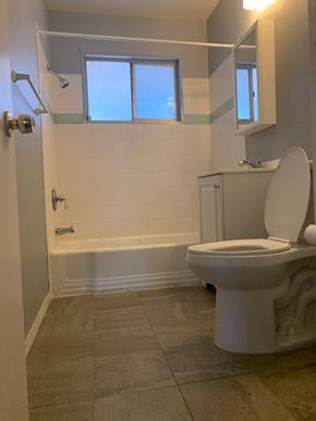 Albuquerque apartment for rent - A white toilet in a bathroom with a white tub and a window.