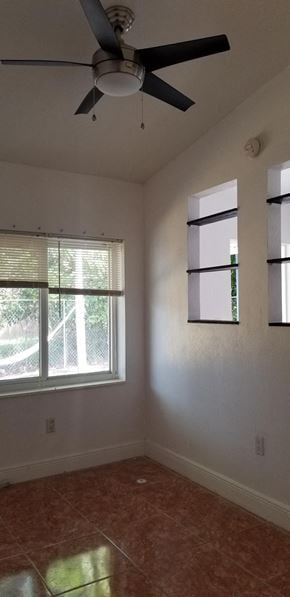 Miami apartment for rent - an empty living room with a ceiling fan and two windows