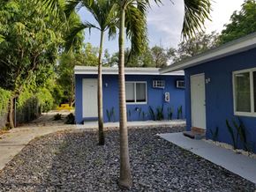 Miami apartment for rent - a blue house with palm trees in front of it