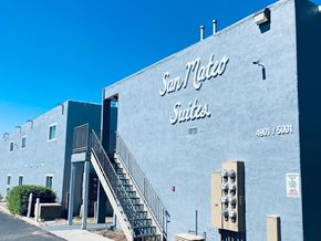 Albuquerque apartment for rent - The San Mateo Suites building has a blue exterior and a staircase leading to the entrance.