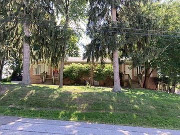 North Canton apartment for rent - A house is surrounded by trees and has a green lawn.