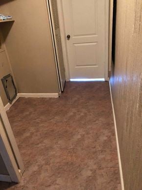 Eunice house for rent - A hallway with a white door and brown carpeting.