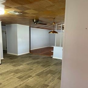 Eunice house for rent - an empty living room with a wood floor and a ceiling fan