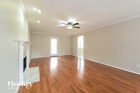 Alabaster house for rent - A spacious room with wooden floors and a fireplace.