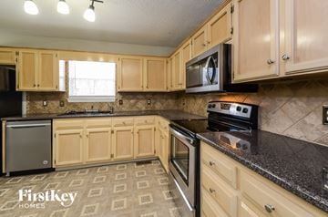 Alabaster house for rent - A kitchen with wooden cabinets and a black countertop.