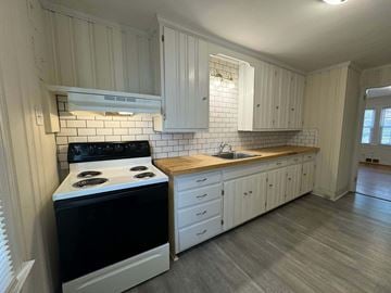 Winston Salem apartment for rent - A kitchen with a black stove top oven and white cabinets.