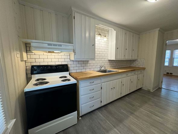 Winston Salem apartment for rent - A kitchen with a black stove top oven and white cabinets.