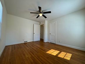 Winston Salem apartment for rent - A room with a ceiling fan and wooden floors.