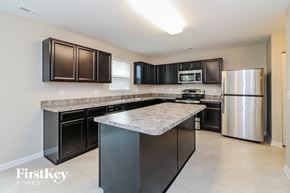 Clayton house for rent - A kitchen with black cabinets and a granite countertop.