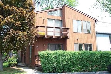 Port Washington apartment for rent - A wooden house with a balcony and a hedge in front.