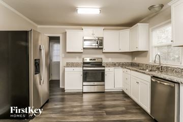 Gastonia house for rent - a kitchen with white cabinets and stainless steel appliances