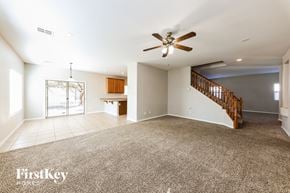 Surprise house for rent - an empty living room with a ceiling fan and a staircase