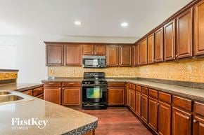 Atlanta house for rent - a kitchen with wood cabinets and black appliances and granite counter tops