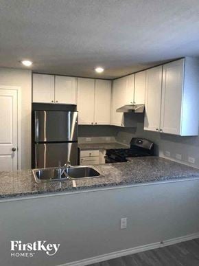 Converse house for rent - a kitchen with white cabinets and a sink and a refrigerator