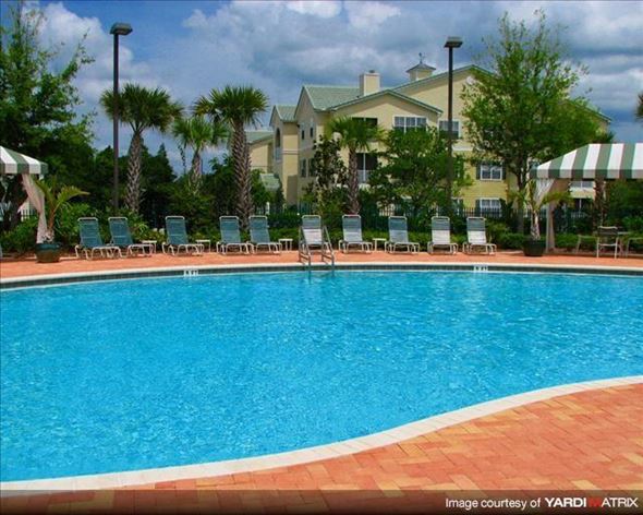 Wesley Chapel apartment for rent - a large swimming pool with chairs and a building in the background
