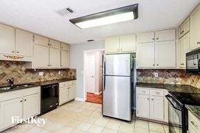Lilburn house for rent - a kitchen with white cabinets and a stainless steel refrigerator