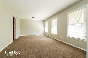 Lilburn house for rent - an empty living room with a carpeted floor and three windows
