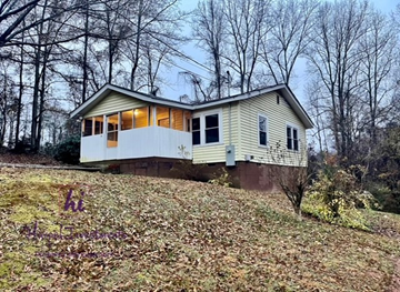 Slater-Marietta house for rent - A house with a white and yellow exterior is surrounded by trees.