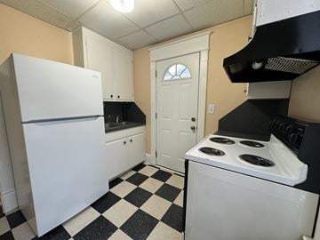 Winston-Salem apartment for rent - A black and white checkered floor in a kitchen with a white fridge and stove.