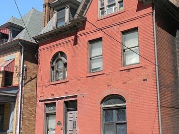 Pittsburgh apartment for rent - A red brick building with a grey door and windows.