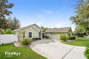 Apopka house for rent - a beige house with a driveway and a white fence