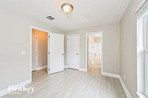 Apopka house for rent - a renovated living room and hallway with white floors and white doors