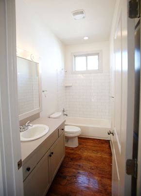New Orleans apartment for rent - A white bathroom with a toilet, sink and a window.