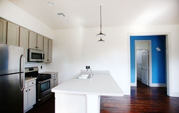 New Orleans apartment for rent - A kitchen with a white island and a black refrigerator.