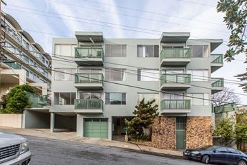 San Francisco apartment for rent - A grey building with green railings and a stone wall.