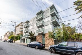 San Francisco apartment for rent - A street view of a residential area with cars parked on the side of the road and apartment buildings in the background.
