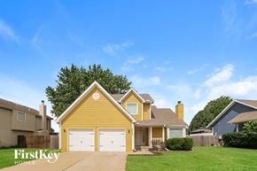 Belton house for rent - a yellow house with white garage doors and a green lawn