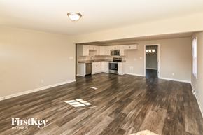 Monroe house for rent - A spacious living room with wooden flooring and a kitchen in the background.