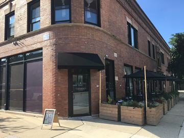 Chicago apartment for rent - A red brick building with a black awning and a sign on the sidewalk.