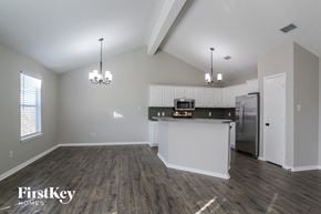 Conroe house for rent - the living room and kitchen of an apartment with white walls and wood flooring