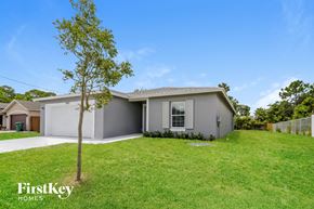 Port St. Lucie house for rent - a beige house with a lawn and a tree