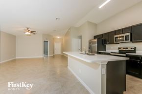 Port St. Lucie house for rent - a kitchen and living room with black appliances and a white counter top