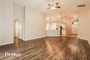 Wesley Chapel house for rent - an empty living room with a ceiling fan and a kitchen
